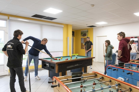 Des jeunes et un éducateur en train de jouer au babyfoot dans le foyer