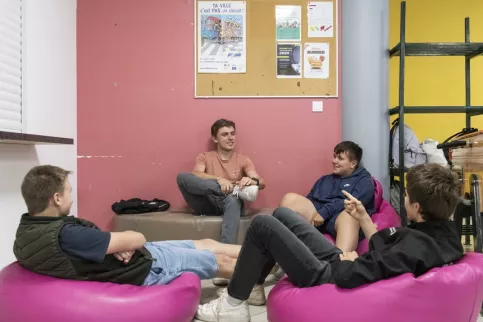 Groupe de jeunes en train de discuter dans des fauteuils du foyer du lycée 