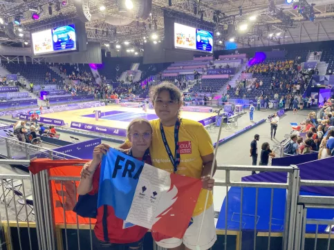 2 jeunes filles tenant le drapeau de l'équipe de France devant le stade