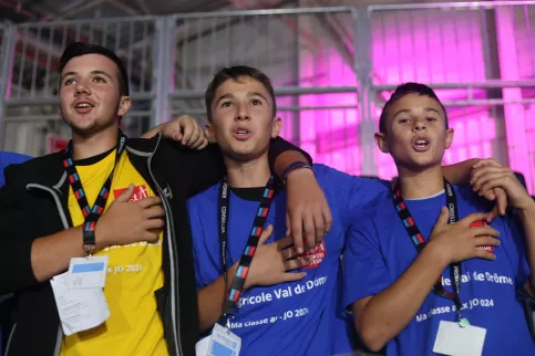 3 jeunes, mains sur la poitrine en train de chanter