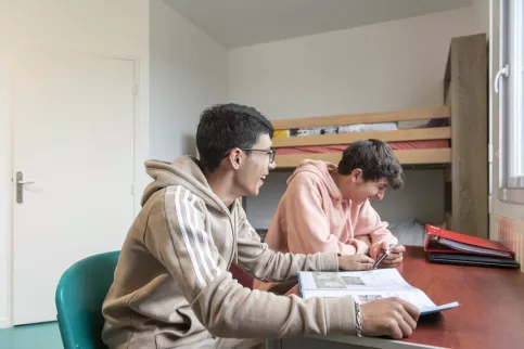 Deux jeunes de l'internat en train de travailler sur le bureau de leur chambre 