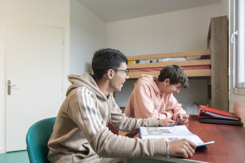 Deux jeunes de l'internat en train de travailler sur le bureau de leur chambre